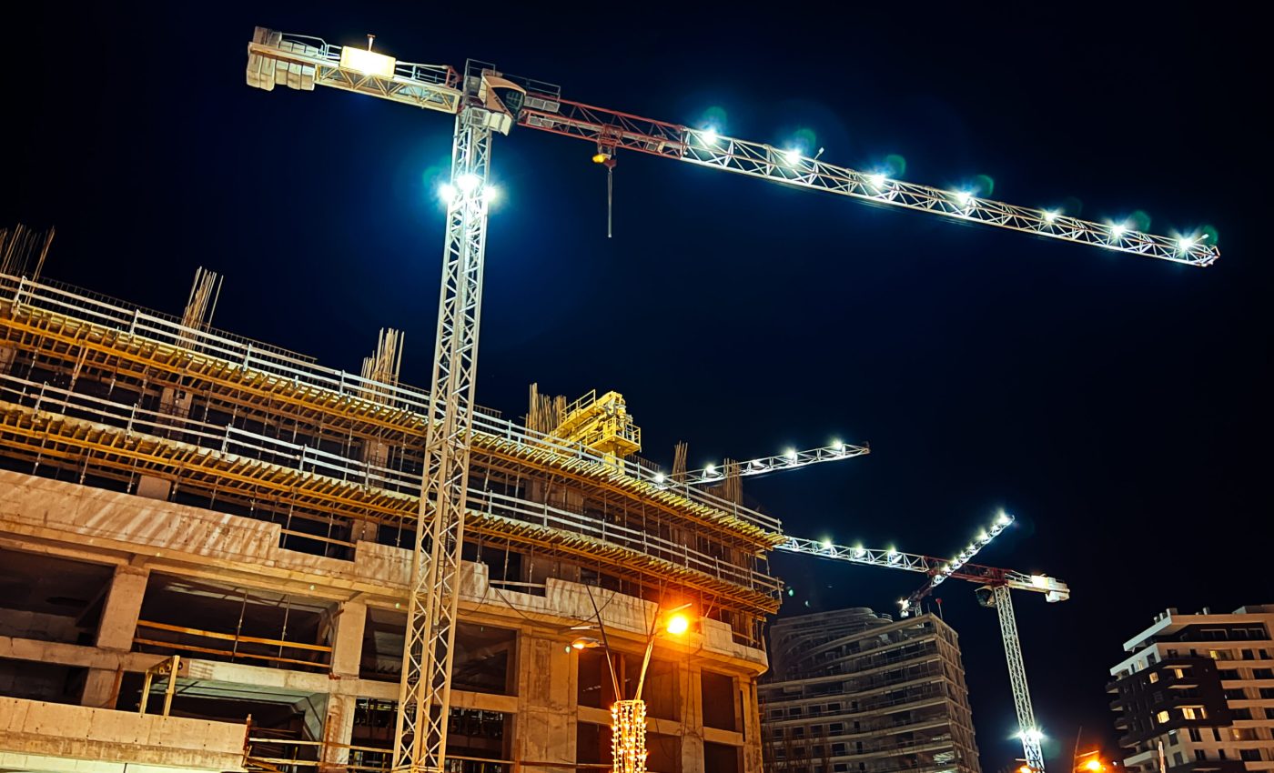 Construction cranes with illumination over multi-storey buildings under construction. High quality photo