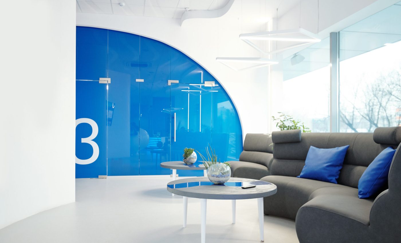 Modern office with cozy lobby furnished with sofa and coffee tables, interior with blue elements